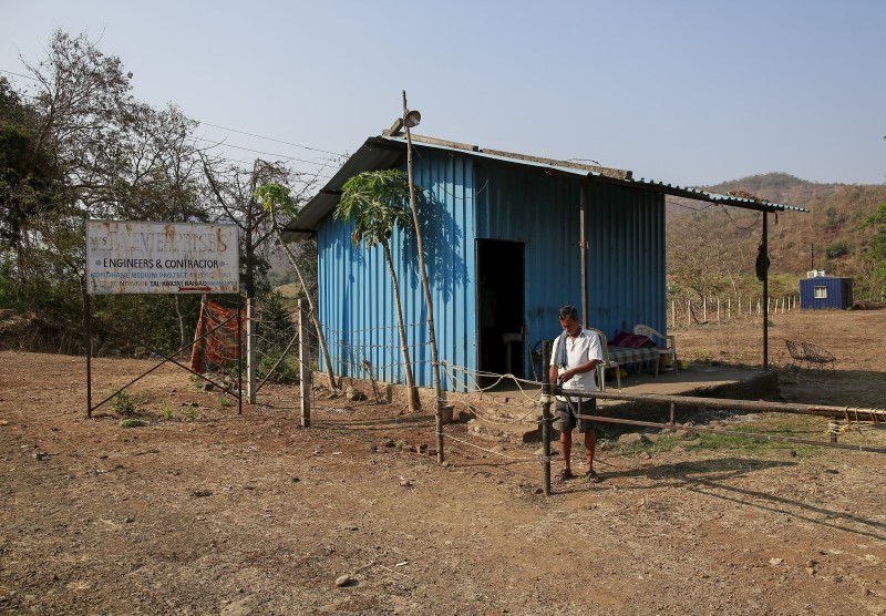 © Reuters. A man stands at a gate at the construction site of the Kondhane Dam in Karjat