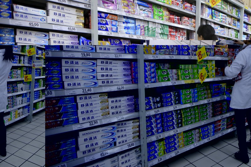 © Reuters. A salesperson arranges toothpaste products on a shelf at a supermarket in Shanghai