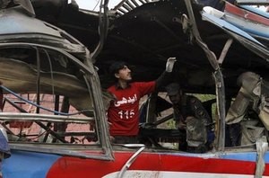 © Reuters. Police and rescue personnel search a bus damaged in a bomb blast in Peshawar