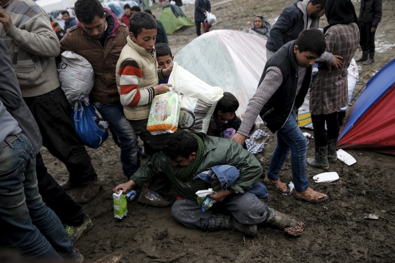 © Reuters. A man falls on the ground as refugees and migrants grab goods donated by volunteers from a truck at a makeshift camp at the Greek-Macedonian border, near the village of Idomeni