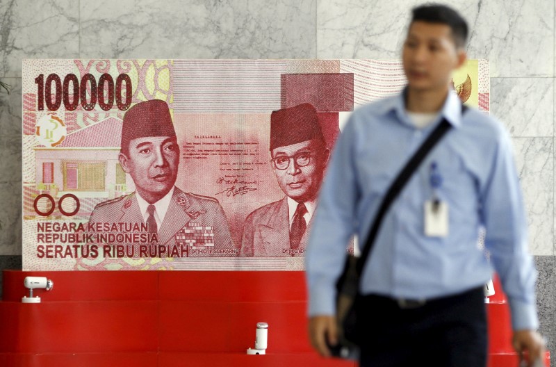 © Reuters. A man walks past a large display of a one hundred thousand rupiah banknote inside the Bank Indonesia complex in Jakarta, Indonesia