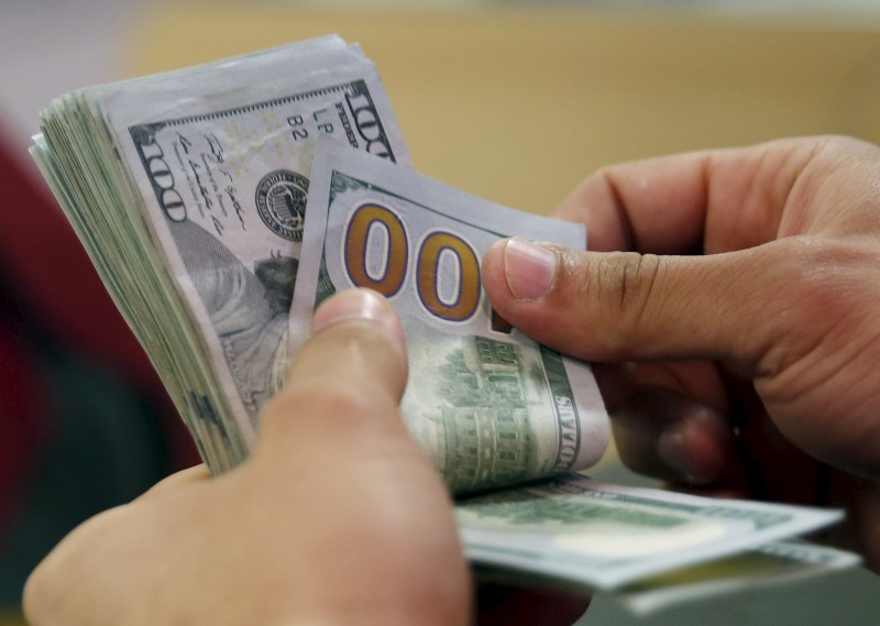 © Reuters. A customer counts his U.S. dollar money in a bank in Cairo