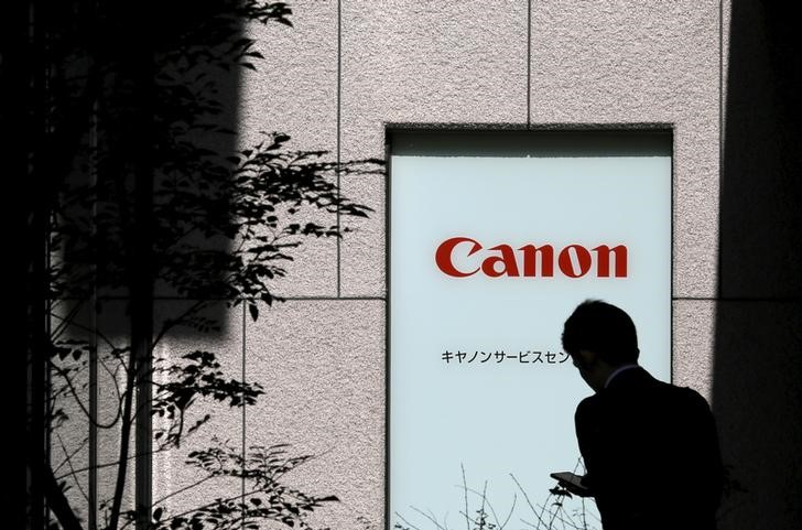 © Reuters. Man walks past a Canon logo in Tokyo