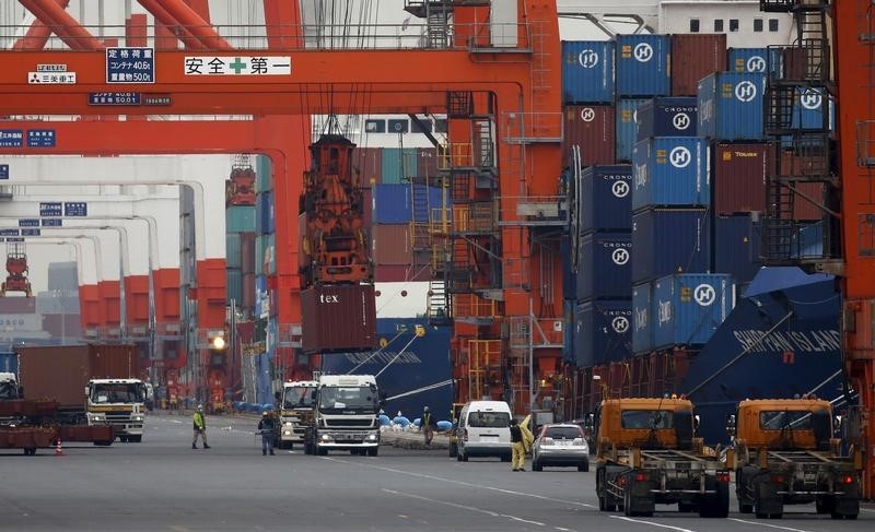 © Reuters. Workers load containers onto trucks from a cargo ship at a port in Tokyo