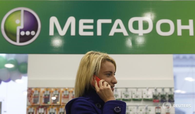 © Reuters. Покупательница разговаривает по телефону в магазине Мегафона в Санкт-Петербурге 