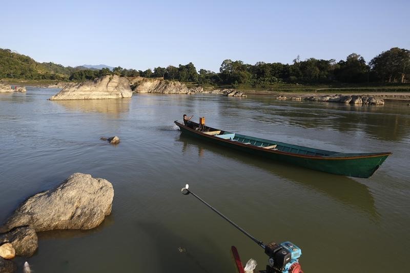 © Reuters. A man steers his boat at Myitsone