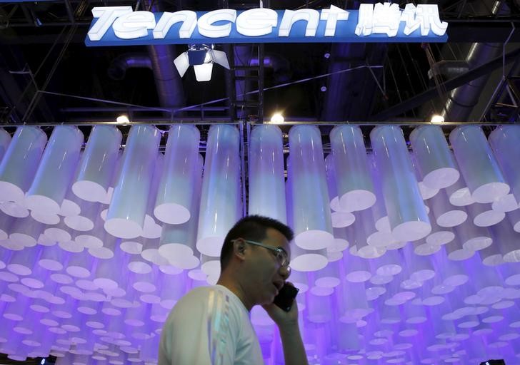 © Reuters. Man uses a mobile phone in front of a logo of Tencent at the Global Mobile Internet Conference (GMIC) 2015 in Beijing