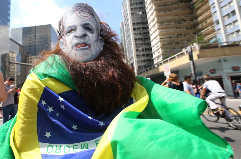 © Reuters. A demonstrator wears a mask with a defaced picture depicting Brazil's former president Luiz Inacio Lula da Silva during a protest over the appointment of Lula da Silva as chief of staff, at Paulista avenue in Sao Paulo