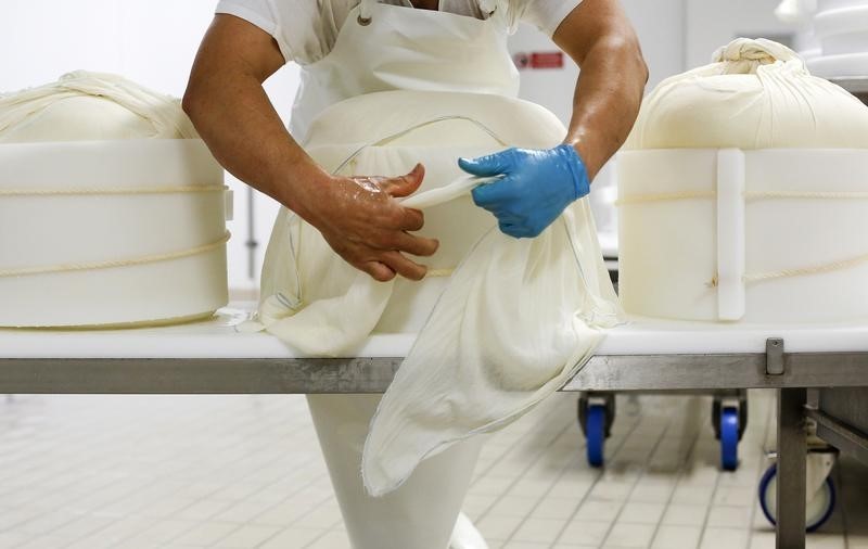 © Reuters. Cheese maker shapes cheese into round Parmesan moulds at 4 Madonne Caseificio dell'Emilia dairy cooperative in Modena