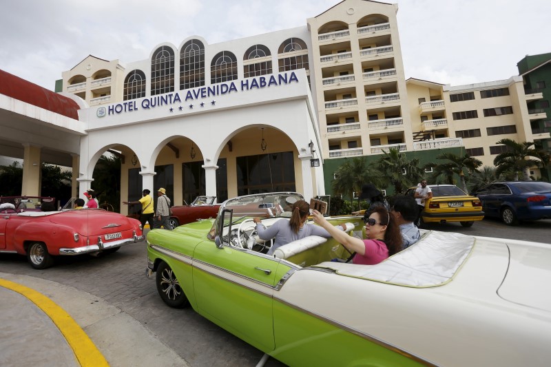 © Reuters. Tourists take a selfie while sitting in a vintage car outside the Quinta Avenida Habana Hotel in Havana