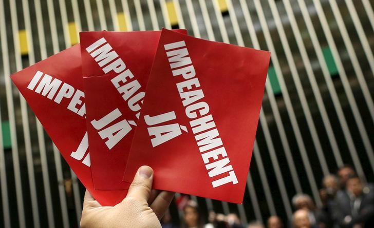 © Reuters. An opposition deputy holds papers that read, "Impeachment now!" during ballot to appoint a committee to report on whether to impeach President Dilma Rousseff at the National Congress in Brasilia