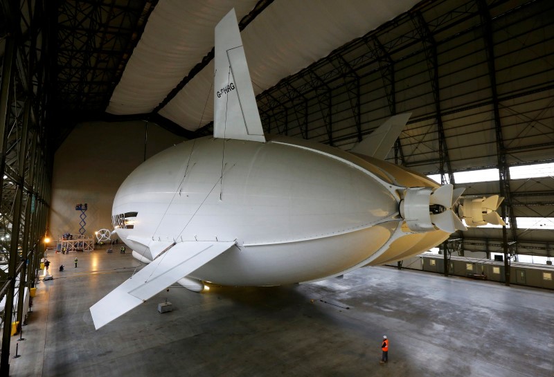 © Reuters. A worker stands under the Airlander 10 hybrid airship during its unveiling in Cardington