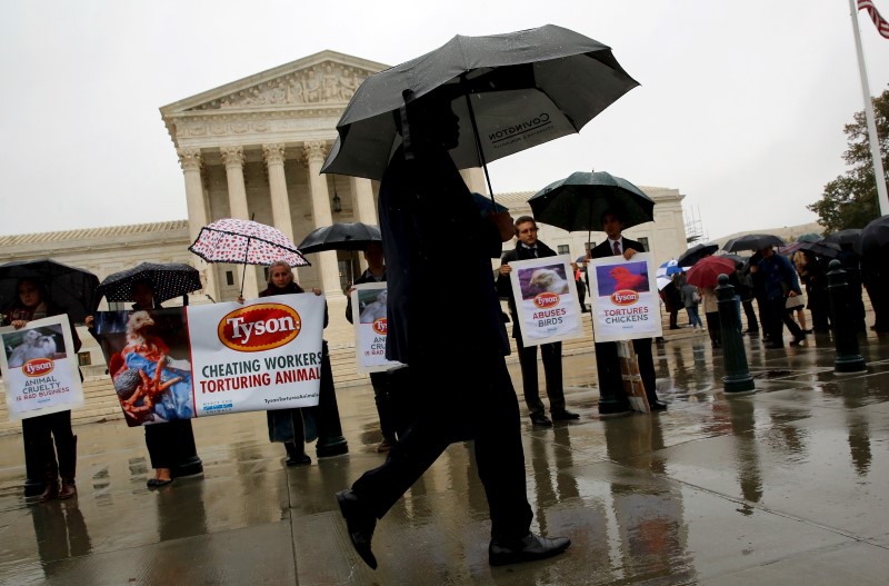 © Reuters. Man walks past people protesting over conditions for Tyson Foods workers and animals outside the U.S. Supreme Court in Washington