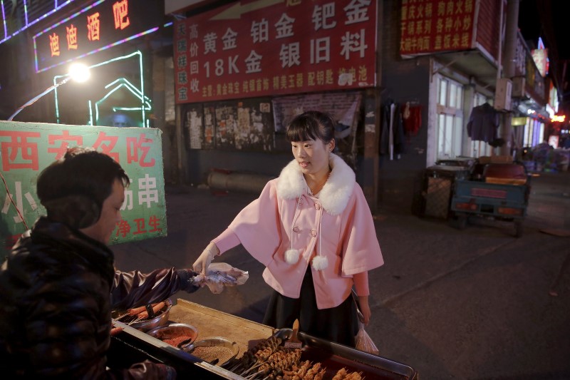 © Reuters. File photo of a girl from Shandong Province buying barbecued meat from a street vendor in Beijing