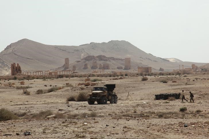 © Reuters. Residents walk near a military truck that belongs to forces loyal to Syria's President Bashar al-Assad, near the historical city of Palmyra