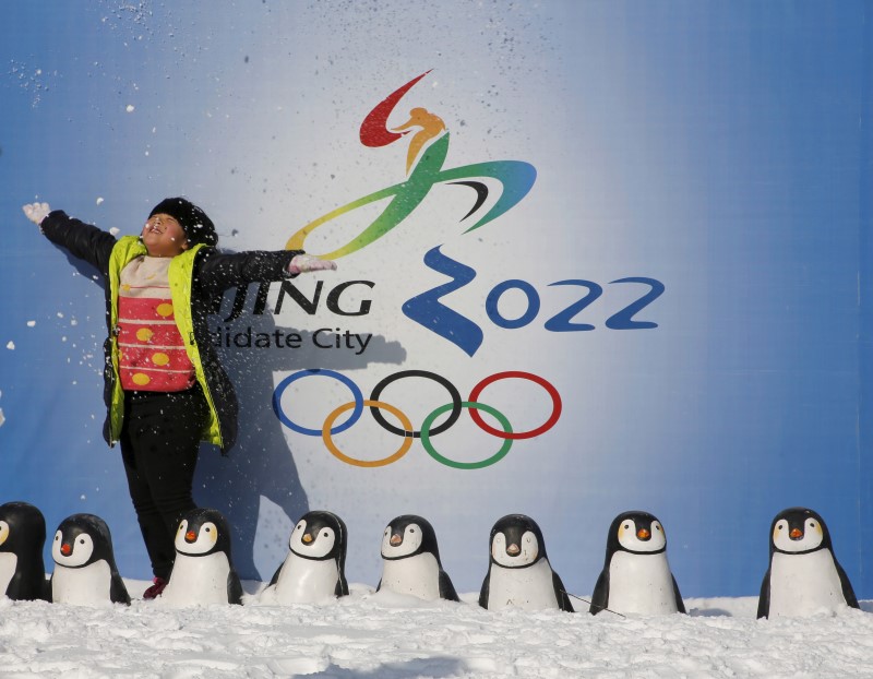 © Reuters. A girl throws snow into the air as she poses for her souvenir picture in front of a board during the Ice and Snow carnival at Taoranting park in Beijing