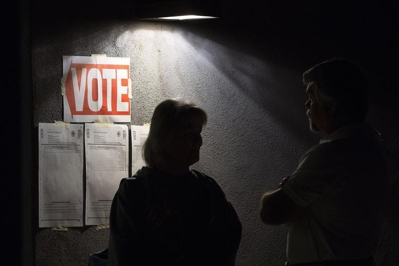 © Reuters. Early morning voters talk as they stand in line before sunrise to vote in Arizona's U.S. presidential primary election at polling station in Cave Creek
