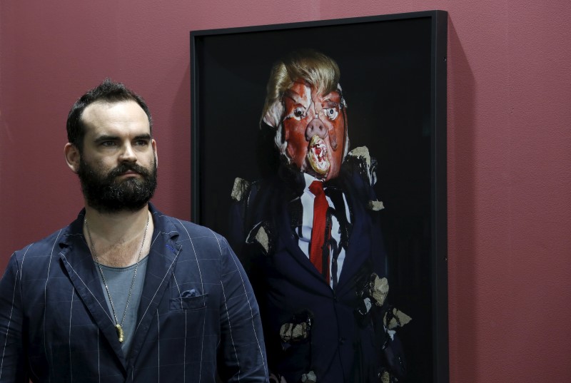 © Reuters. British artist James Ostrer poses beside a photo taken by him of his creation entitled "Emotional Download" during an art exhibition in Hong Kong