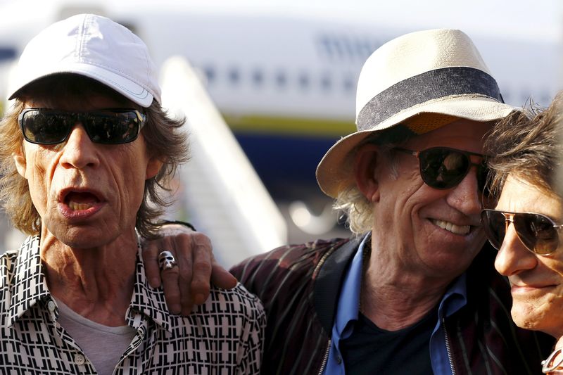 © Reuters. Jagger, Richards and Wood of the Rolling Stones talk with the media after landing in Havana