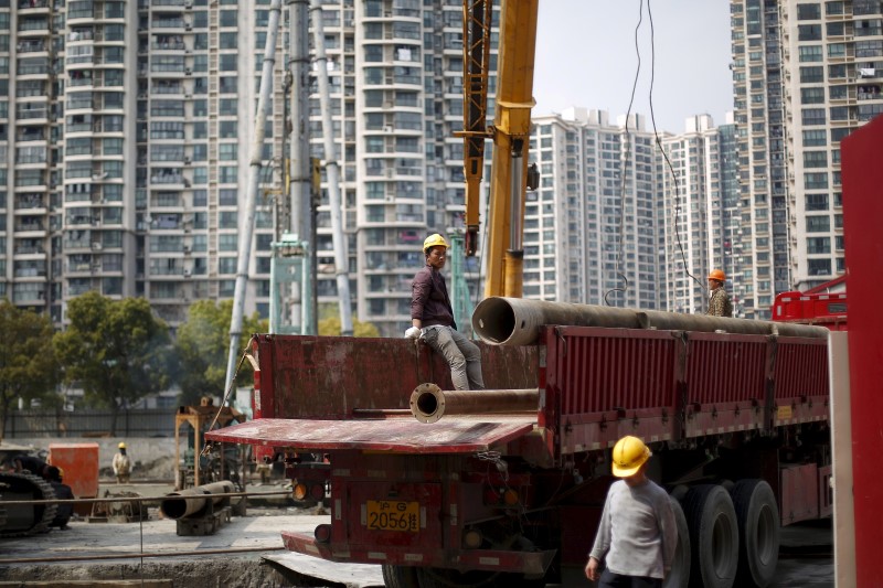 © Reuters. File photo of labourers working at a construction site in front of residential buildings in Shanghai