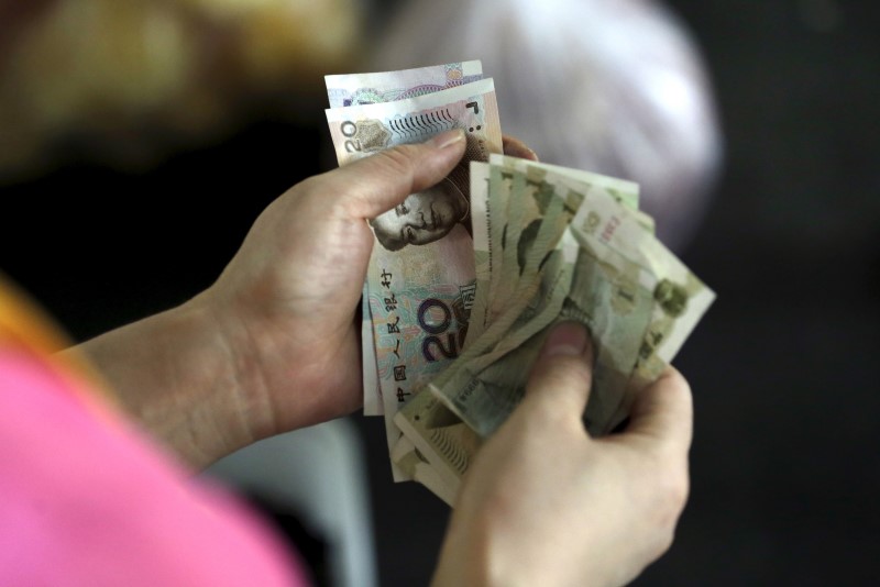 © Reuters. A customer counts Chinese Yuan notes at a market in Beijing