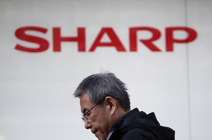 © Reuters. A pedestrian walks under a logo of Sharp Corp outside an electronics retail store in Tokyo