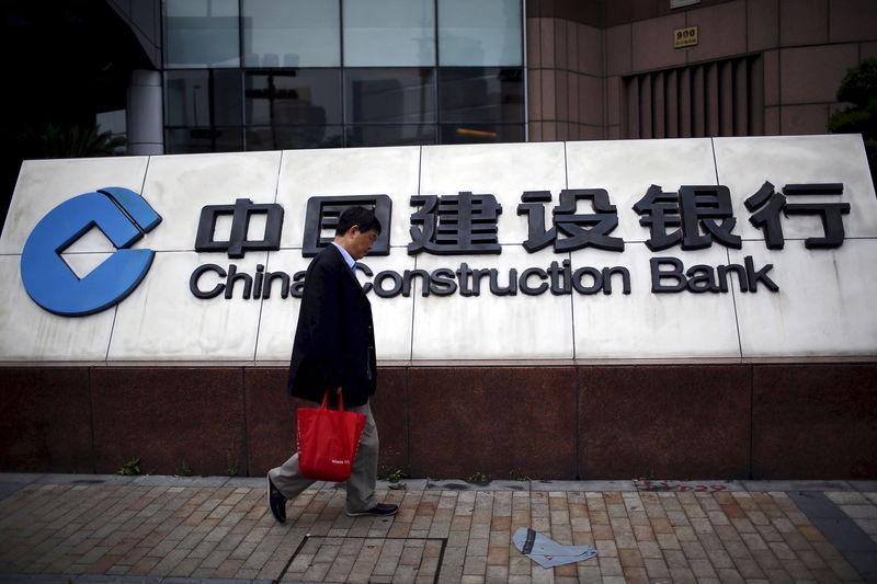 © Reuters. File photo of a man walking past a logo of China Construction Bank at the Pudong financial area in Shanghai