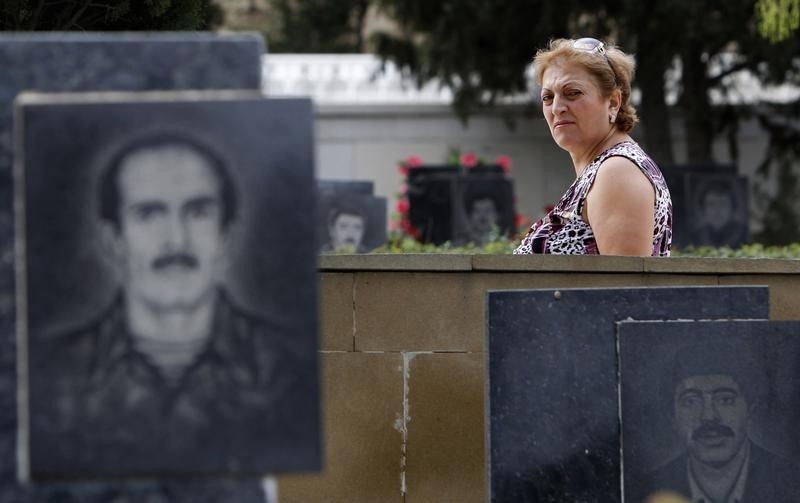 © Reuters. A woman walks past tombstones with portraits of Azeris killed during the fighting between Karabakh and Azerbaijan forces in 1993 in the Alley of Martyrs memorial cemetery in Baku