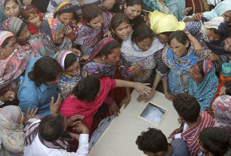 © Reuters. Family members mourn as they gather near body of a relative, killed in a blast outside a public park on Sunday, during funeral in Lahore