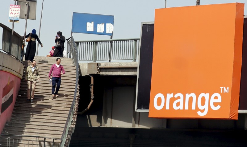 © Reuters. People walk past a sign of French telecom operator Orange hanging from a bridge in Cairo, Egypt
