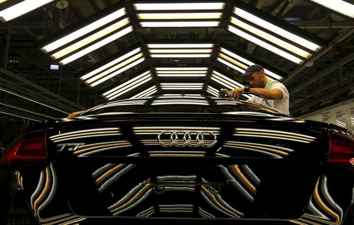 © Reuters. A worker stands next to a car on the assembly line as serial production of the new Audi TT roadster starts at the Audi plant in Gyor, west of Budapest 