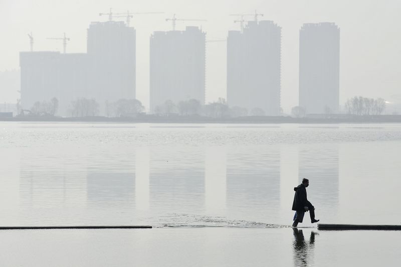 © Reuters. A man walks in an artificial lake near residential buildings in Taiyuan