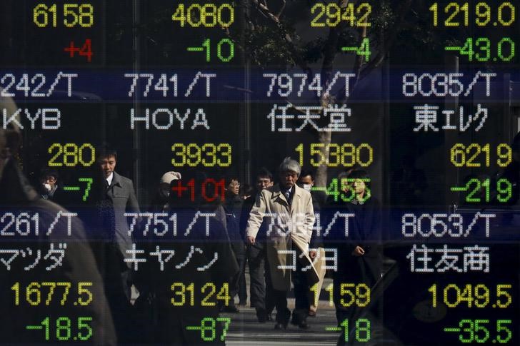 © Reuters. People are reflected in a display showing market indices outside a brokerage in Tokyo