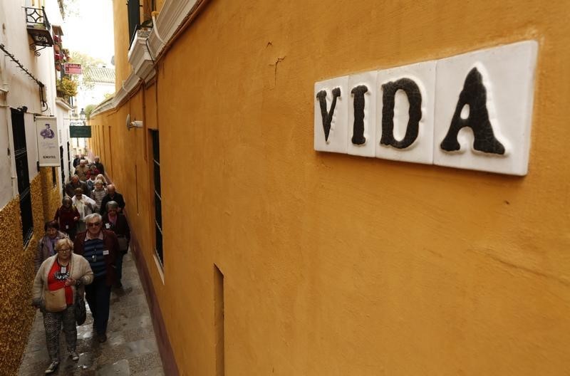 © Reuters. Tourists walk on the narrow Vida (Life) street located in the Santa Cruz neighborhood in the Andalusian capital of Seville, southern Spain