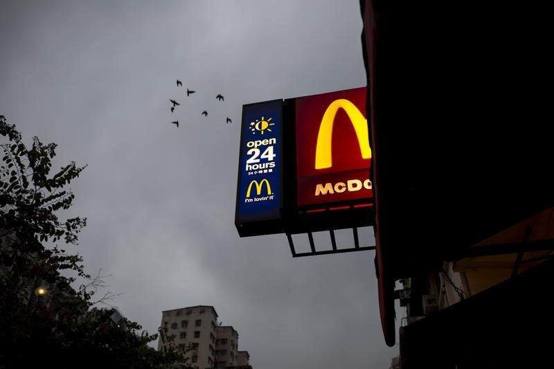 © Reuters. Birds fly past a sign of 24-hour McDonald's restaurant at sunrise in Hong Kong, China