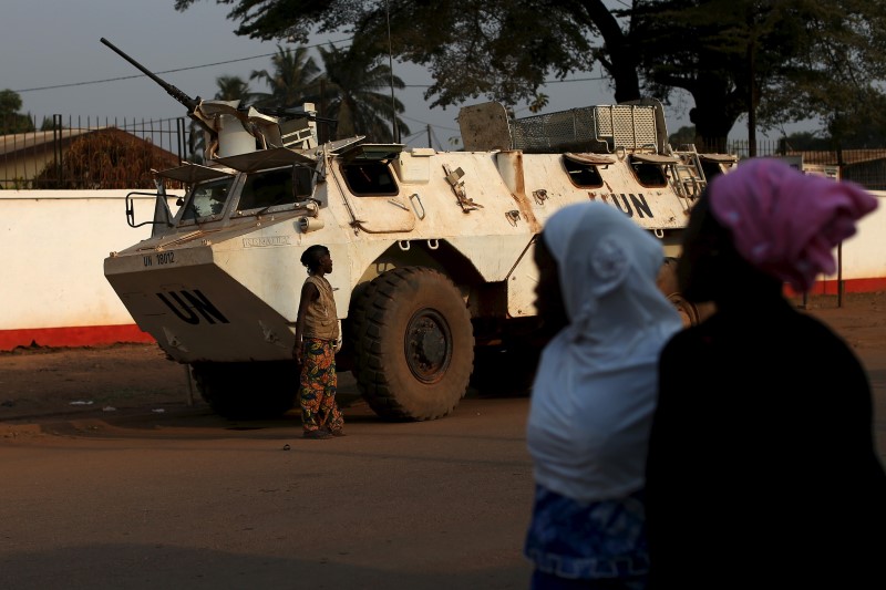 © Reuters. Women walk by a U.N. peacekeeping armoured vehicle in the mostly muslim PK5 neighbourhood of Bangui