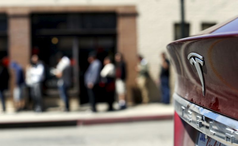 © Reuters. The Tesla logo of a parked vehicle is pictured as people wait in line near a Tesla Motors store to place deposits on the electric car company's mid-priced Model 3 which is expected to cost around $35,000 in Pasadena