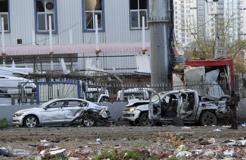 © Reuters. A member of the police special forces stands next to vehicles, which were damaged by a car bomb attack that targeted a minibus carrying members of the police special forces, occurred in Diyarbakir