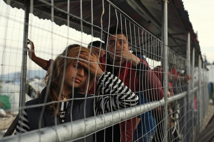 © Reuters. Imigrantes e refugiados em cerca na fronteira entre Grécia e Macedônia