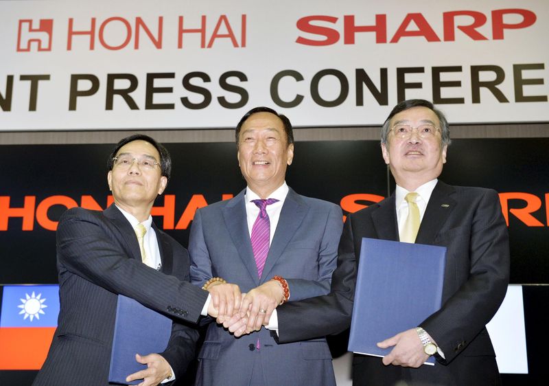 © Reuters. Founder and Chairman of Taiwan's Foxconn shakes hand with the company Vice Chairman and Japan's Sharp Corp Chief Executive at their joint news conference in Sakai