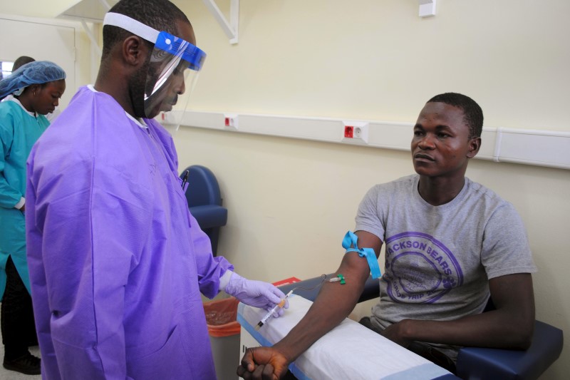 © Reuters. A healthcare worker takes a blood sample from an Ebola survivor as part of a study on the disease, in Monrovia, Liberia