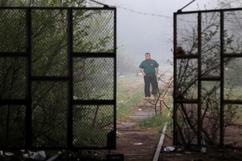 © Reuters. A man walks along railway tracks at a makeshift camp for migrants and refugees at the Greek-Macedonian border near the village of Idomeni