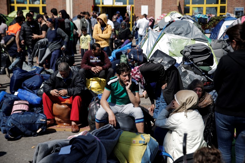 © Reuters. Refugiados e inmigrantes, sentados entre sus pertenencias antes de abordar un autobús hacia otras partes del país donde serán acomodados, en el Puerto del Pireo, cerca de Atenas