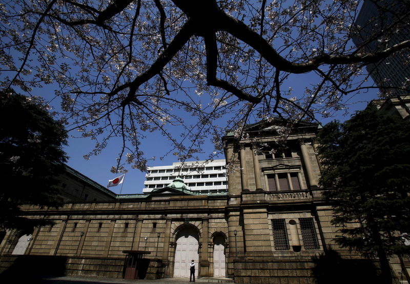 © Reuters. A security officer stands guard near half-blooming cherry blossoms, outside the Bank of Japan headquarters in Tokyo