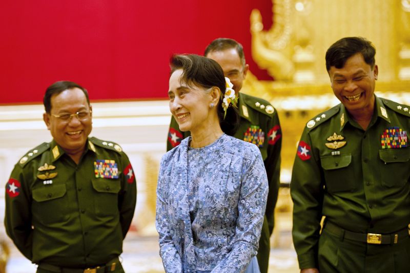 © Reuters. Myanmar's NLD party leader Aung San Suu Kyi smiles with army members during the handover ceremony of outgoing President Thein Sein and new President Htin Kyaw at the presidential palace in Naypyitaw