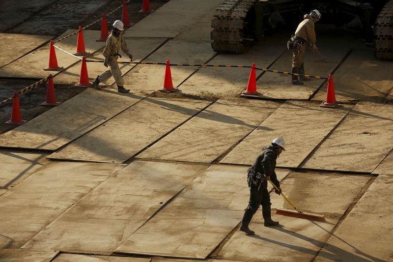 © Reuters. Workers sweep a construction site in Tokyo