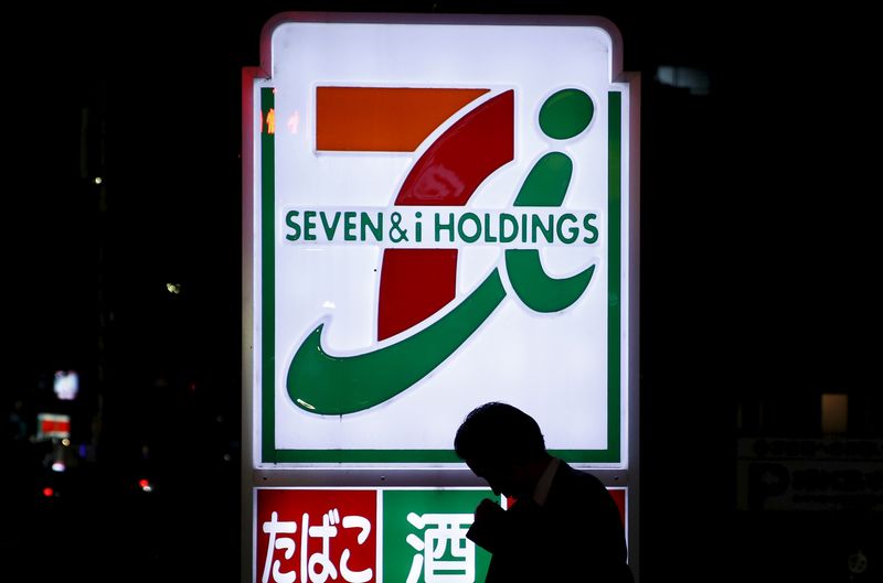 © Reuters. A pedestrian walks in front of a signboard of Seven & I Holdings' 7-Eleven convenience store in Tokyo