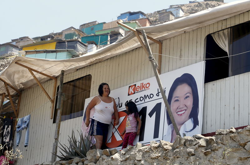 © Reuters. Luz Malhaber walks outside her house next to a electoral sign of Peru's presidential candidates Keiko Fujimori of 'Fuerza Popular' party in San Juan de Miraflores on the outskirts of Lima