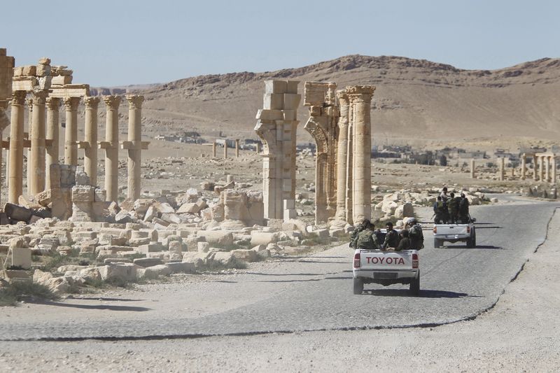 © Reuters. A file photo of Syrian army soldiers driving past the Arch of Triumph in the historic city of Palmyra, in Homs Governorate