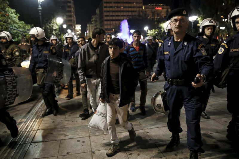 © Reuters. Imigrantes e policiais vistos no porto de Pireu